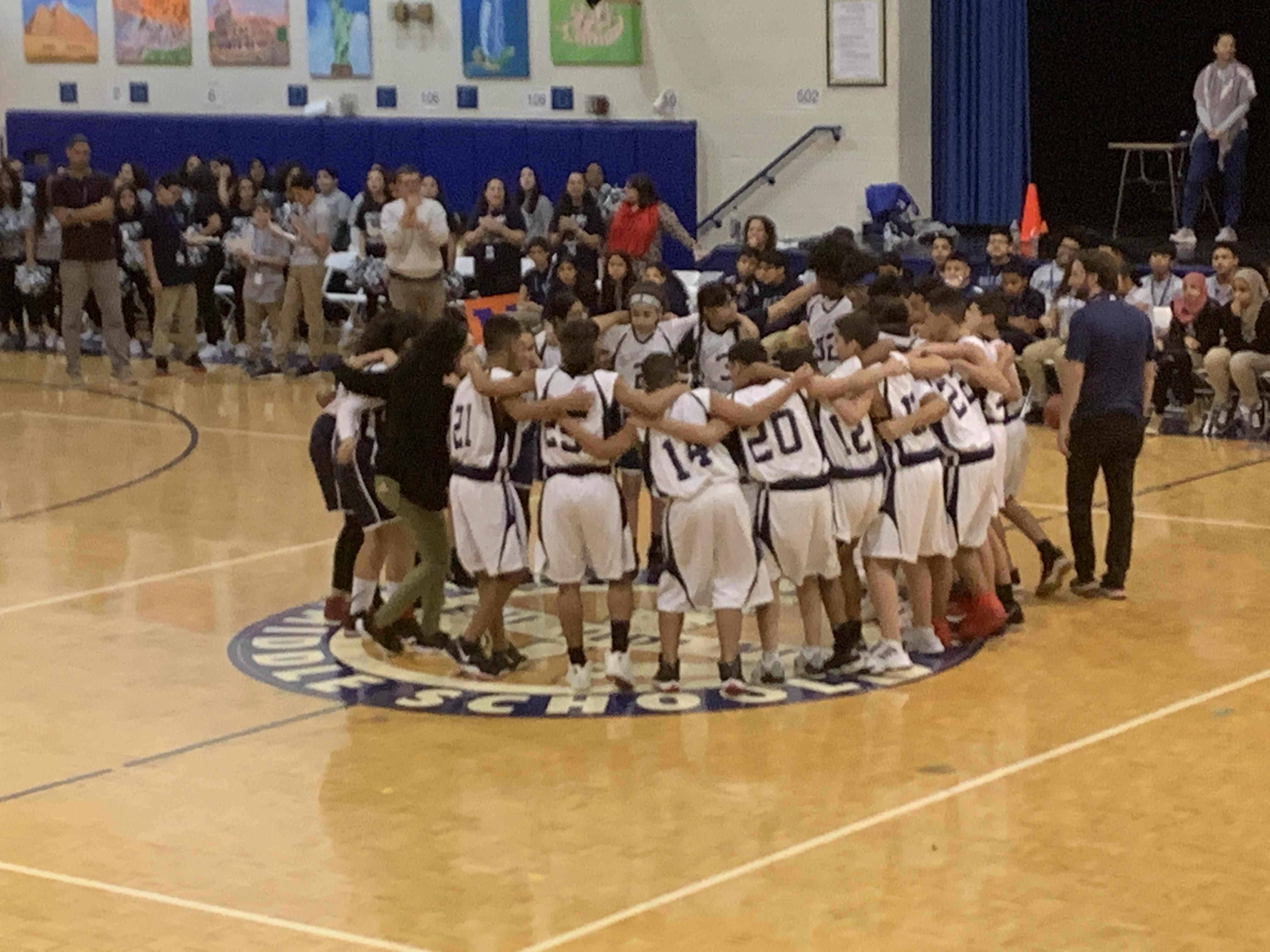boys & girls basketball players in a huddle